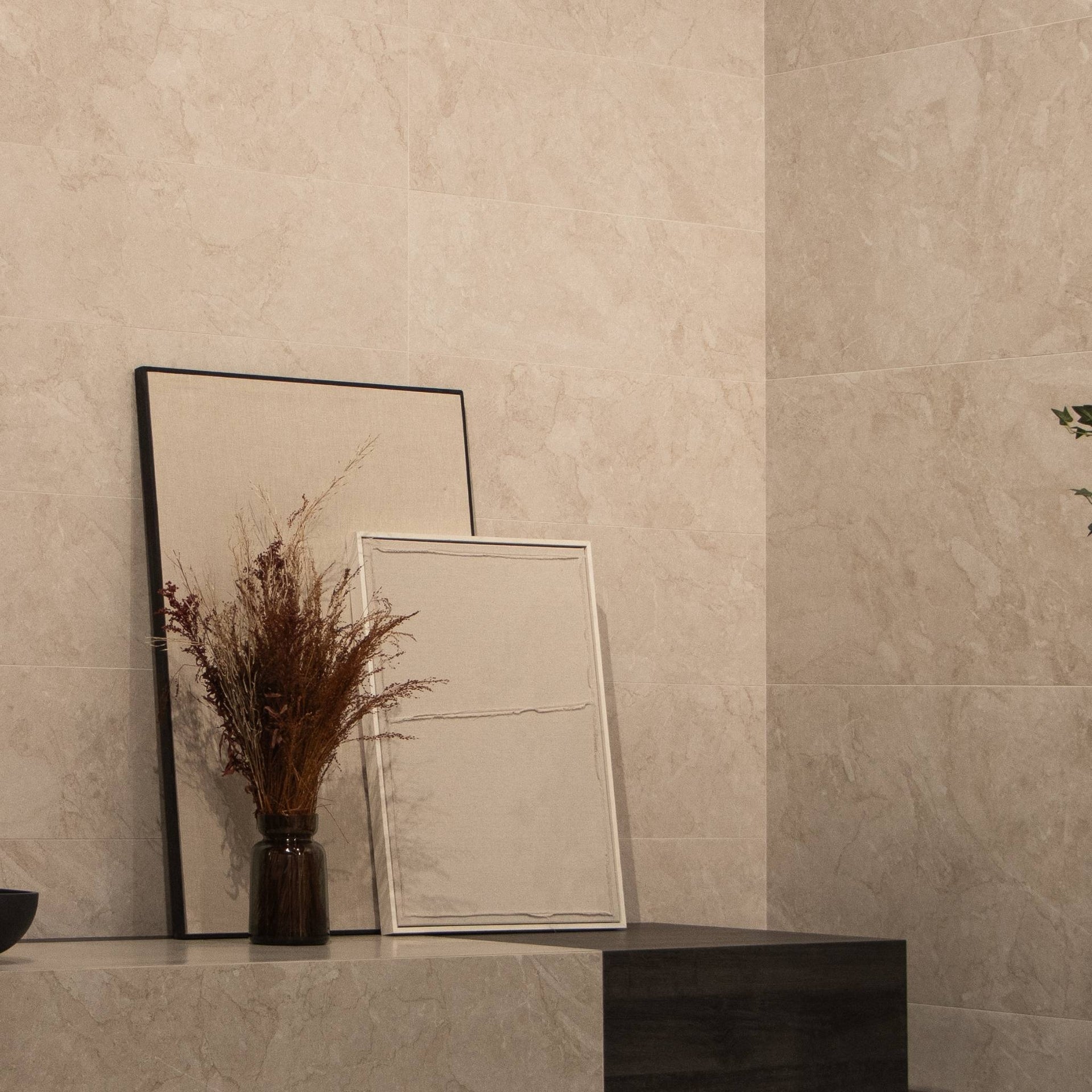 Living area with two framed pictures on a ledge against a Pensford sand stone-effect tiled wall.