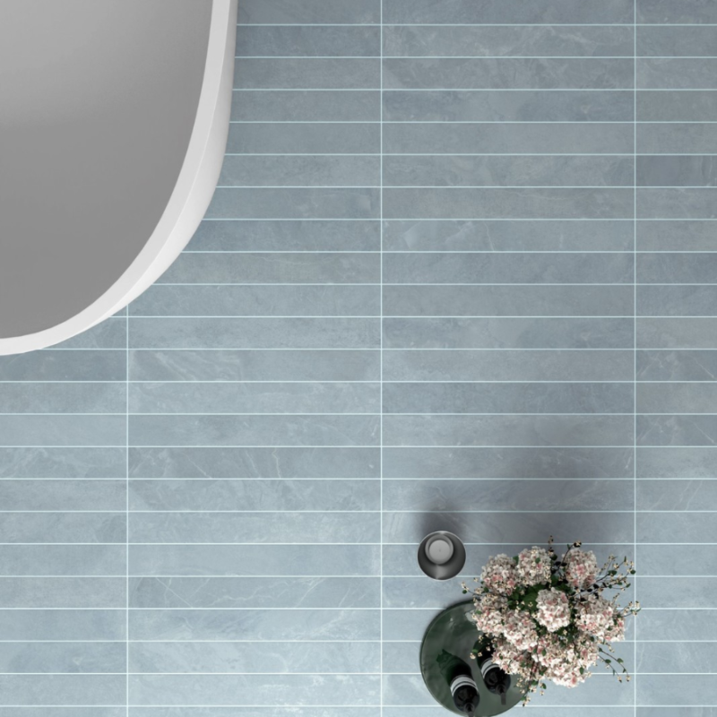 Blue tiled floor seen from above, with the curved edge of a bath and a vase of flowers.
