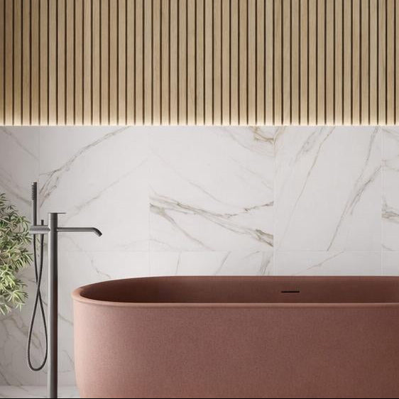 close up of the modern bathroom with a brown freestanding bathtub, white marble with silver and gold veining on wall, and wooden accents.