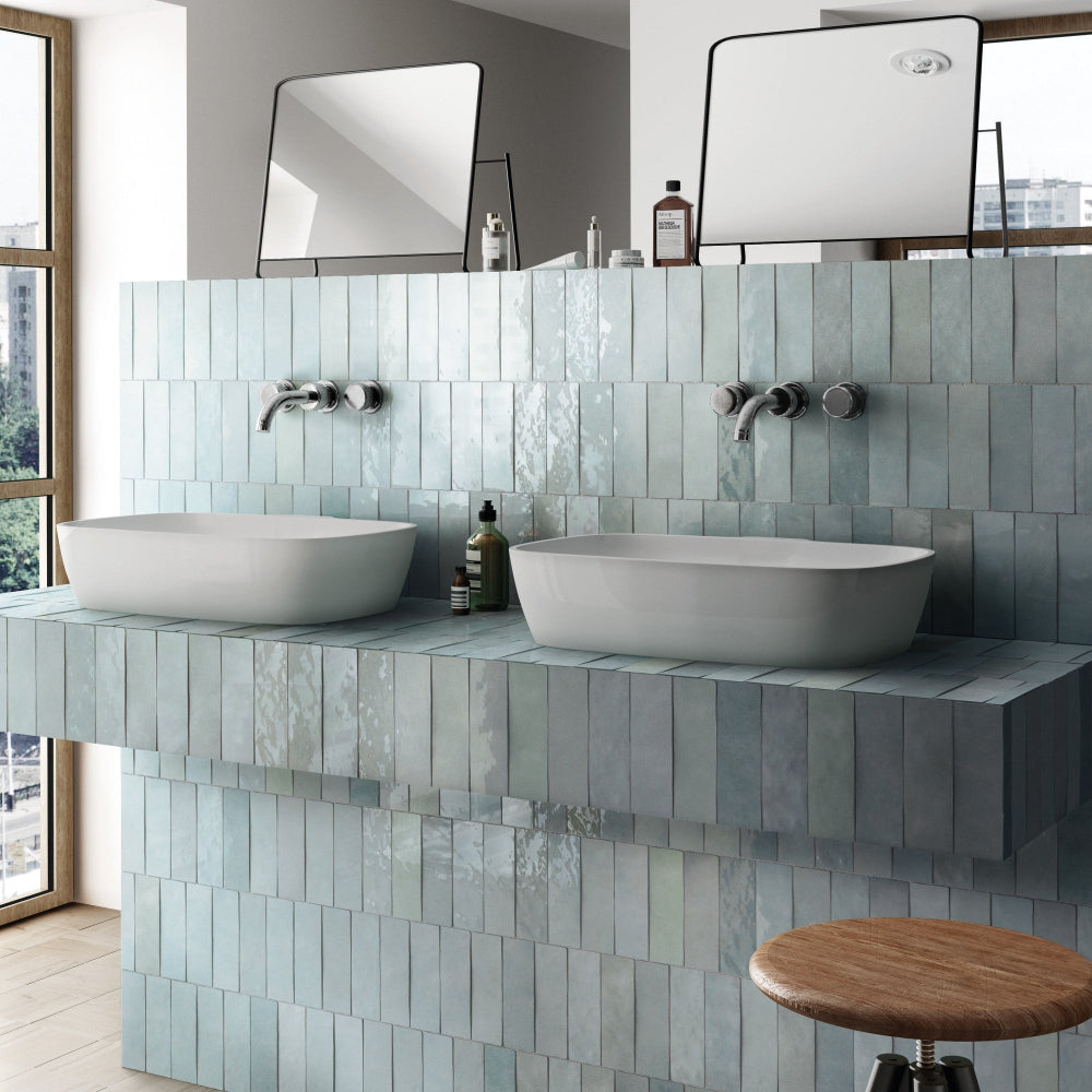 Modern bathroom with two oval sinks against a tiled wall.