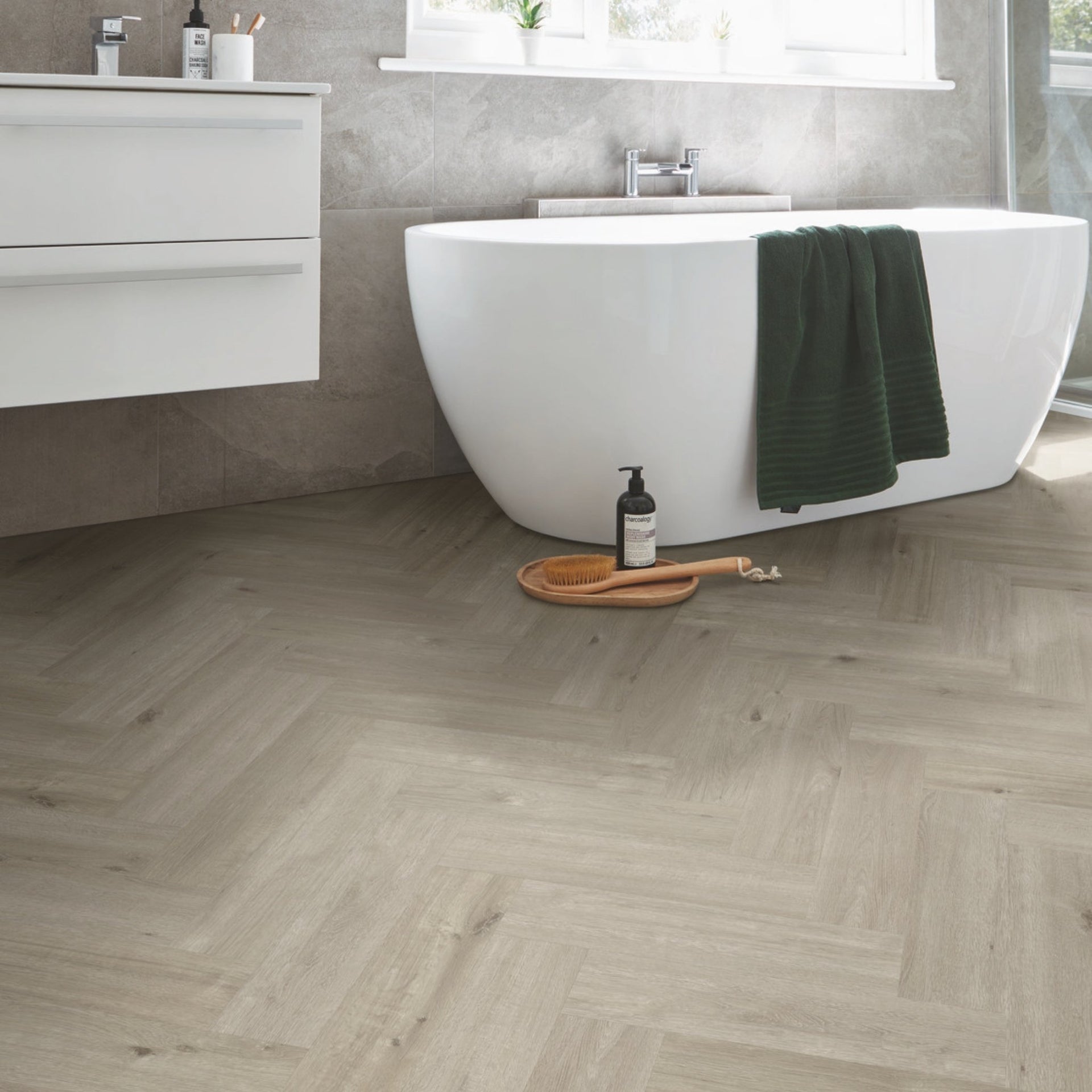 Bathroom with a freestanding bathtub, wooden floor, and white vanity on herringbone style, greige wood effect luxury vinyl tiles. 

layout-bathroom