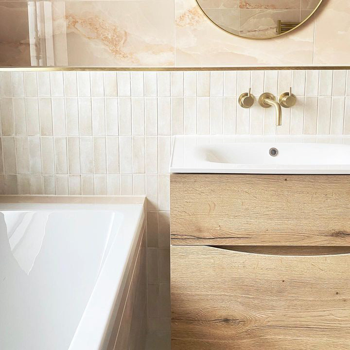 Aruba Cream gloss and Newland pink in bathroom setting with brass taps and wooden cabinet