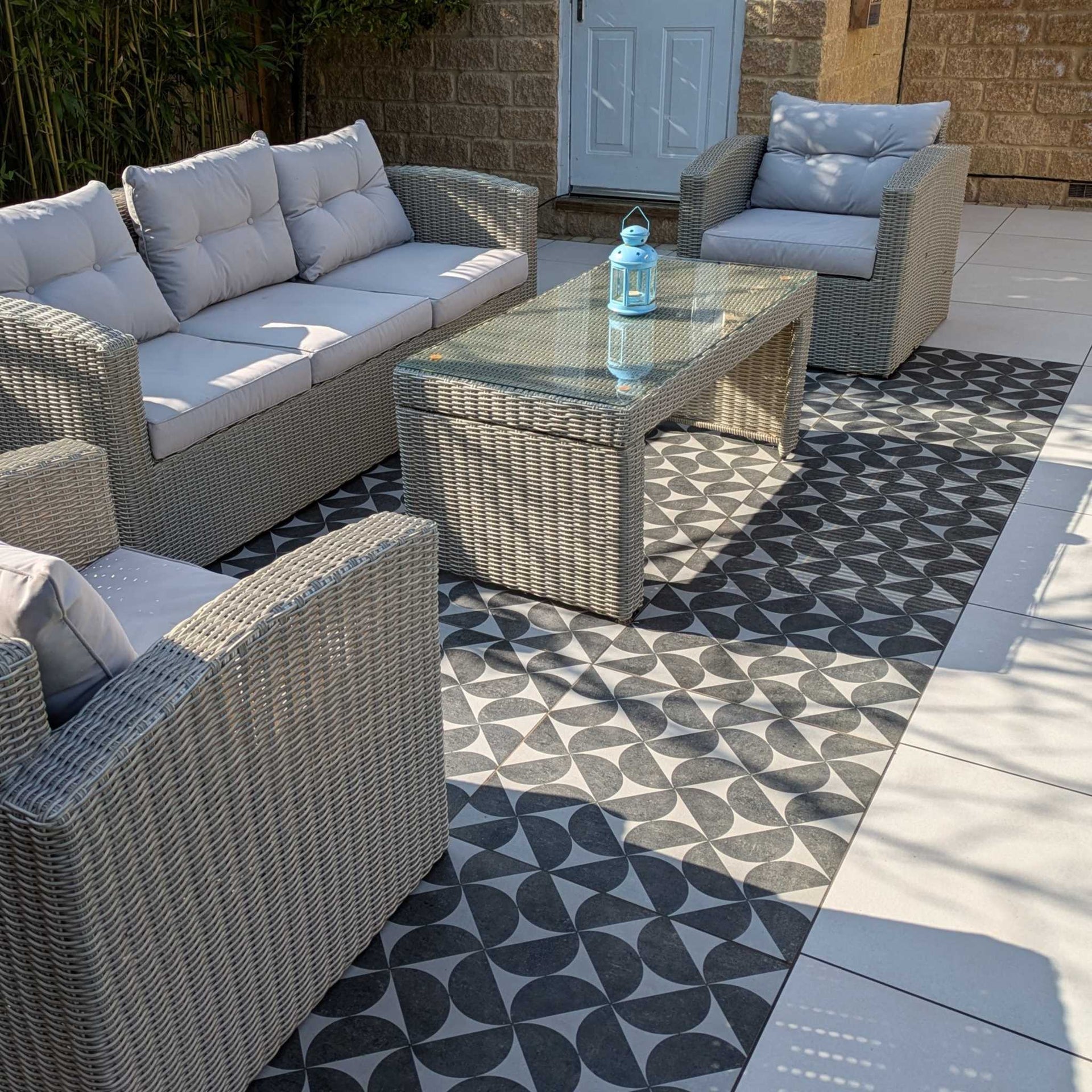 Outdoor patio furniture set with a glass table on a bodrum eclipse grey patterned patio floor.