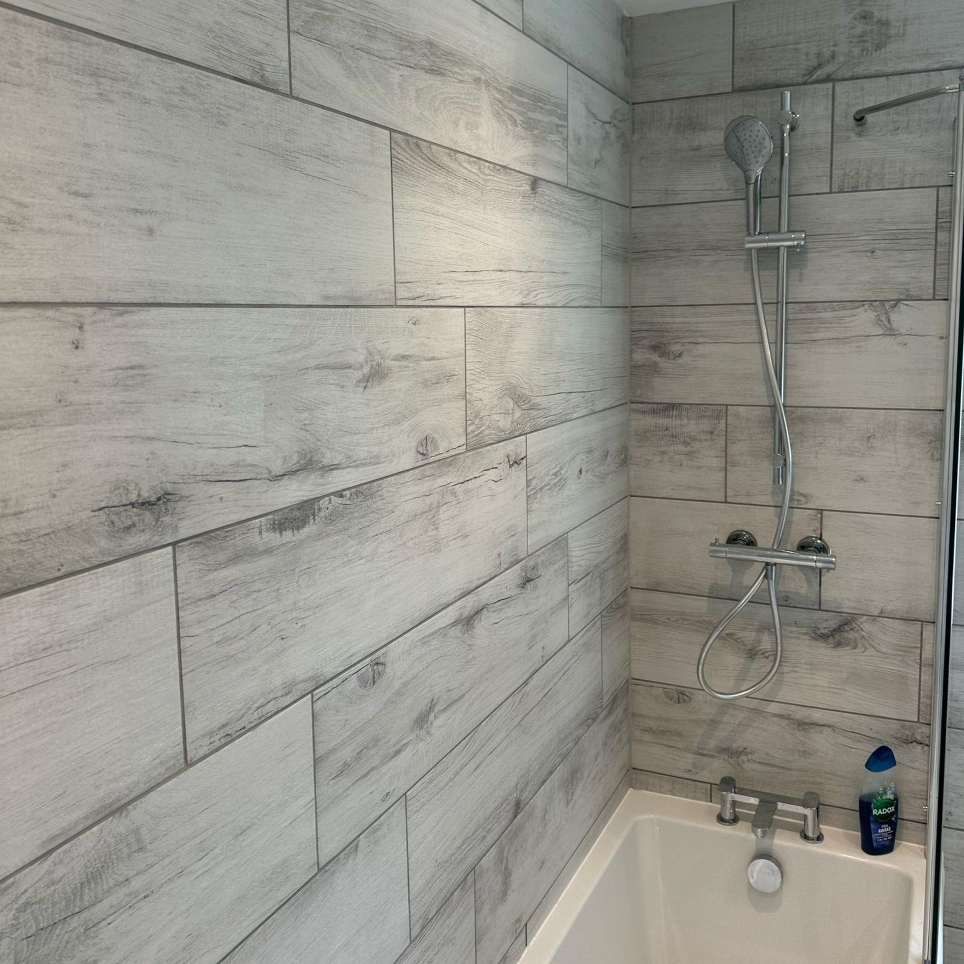 Bathroom with white wood effect tiled walls and a shower setup. layout-bathroom