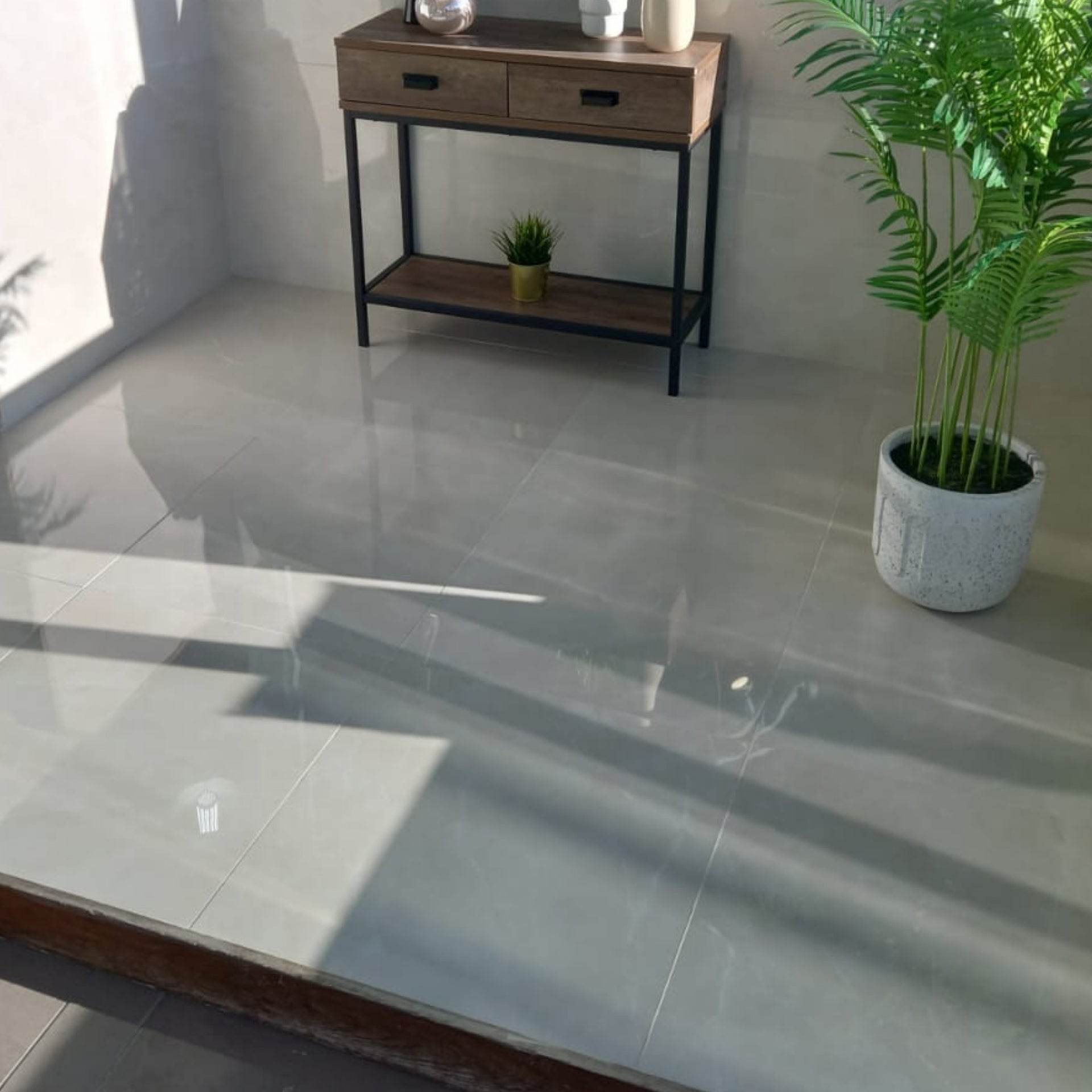 Modern interior with a langstone polished beige tiled floor, small table, and potted plant.