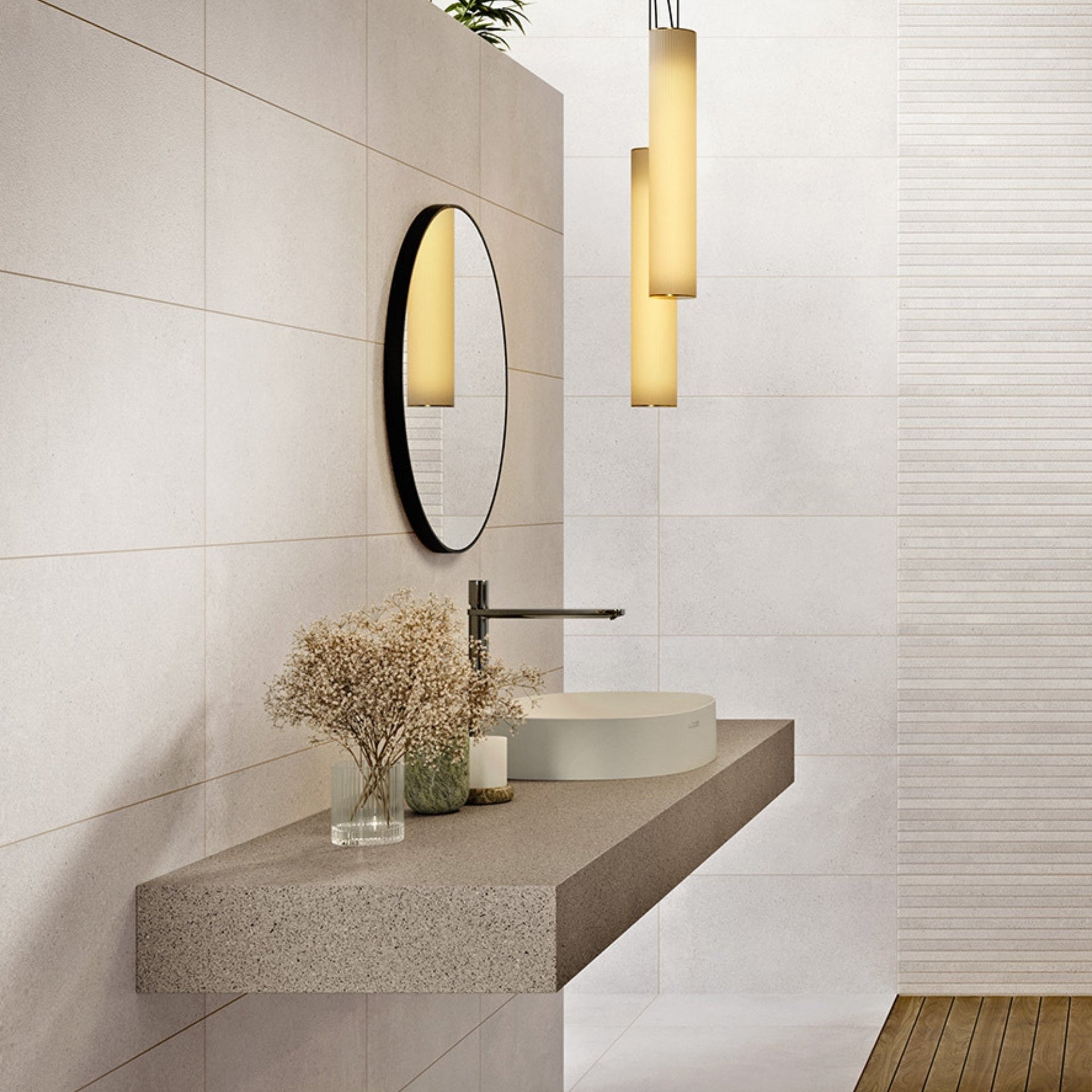 cream stone effect wall tiles on a modern bathroom with a floating concrete vanity, round mirror, and pendant lights.