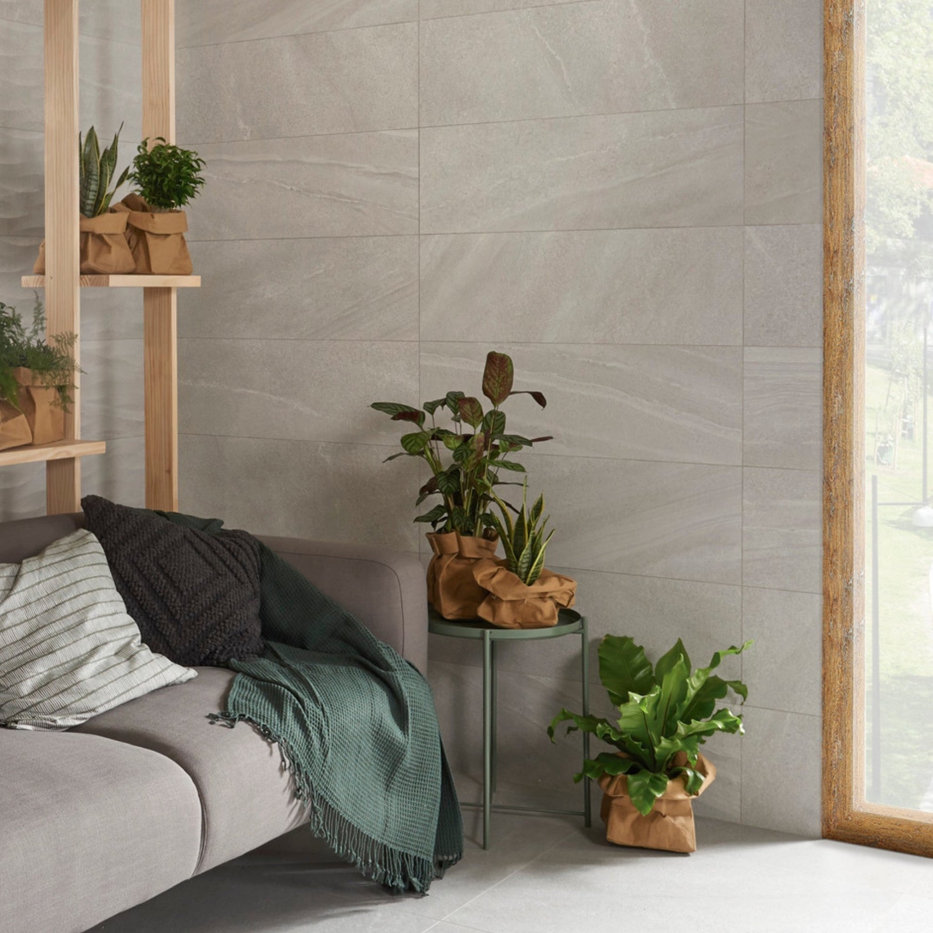 Living room with a sofa, plants, and a peawrl light grey stone effect tiled wall.