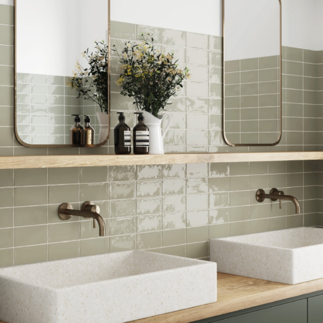 Bathroom with glossy green tiled walls, white sinks, brass elements.

 layout-bathroom