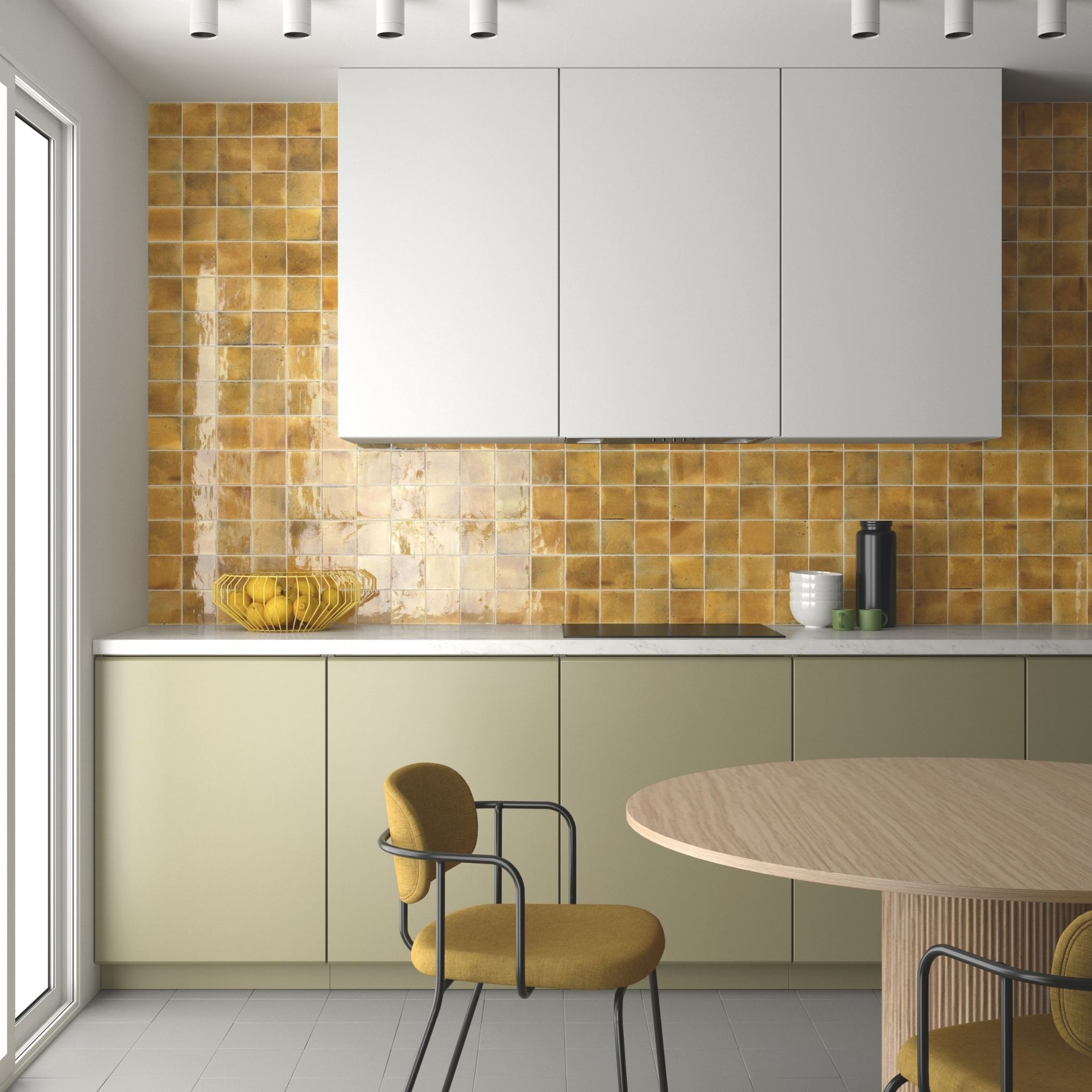 A modern kitchen interior with white upper cabinets, warm yellow-gold santiago zellige square tile backsplash, cream lower cabinets, a light wood dining table, and mustard-yellow chairs.