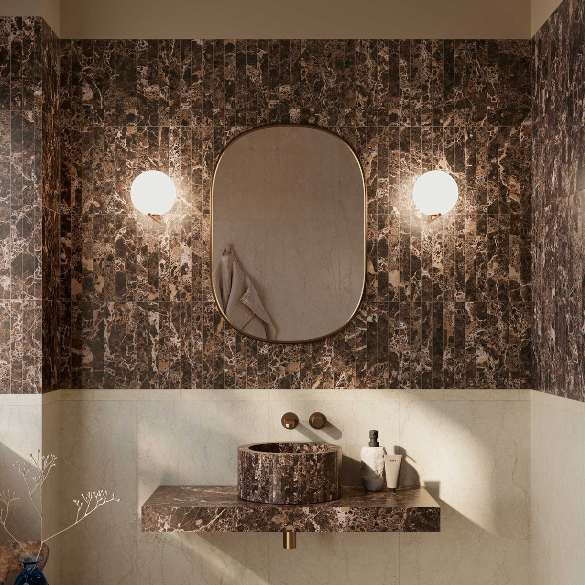 A bathroom vanity featuring a dark brown and black marble sink and matching floating countertop, set against a matching marble backsplash wall with a central oval mirror and two glowing wall sconces.

layout-bathroom