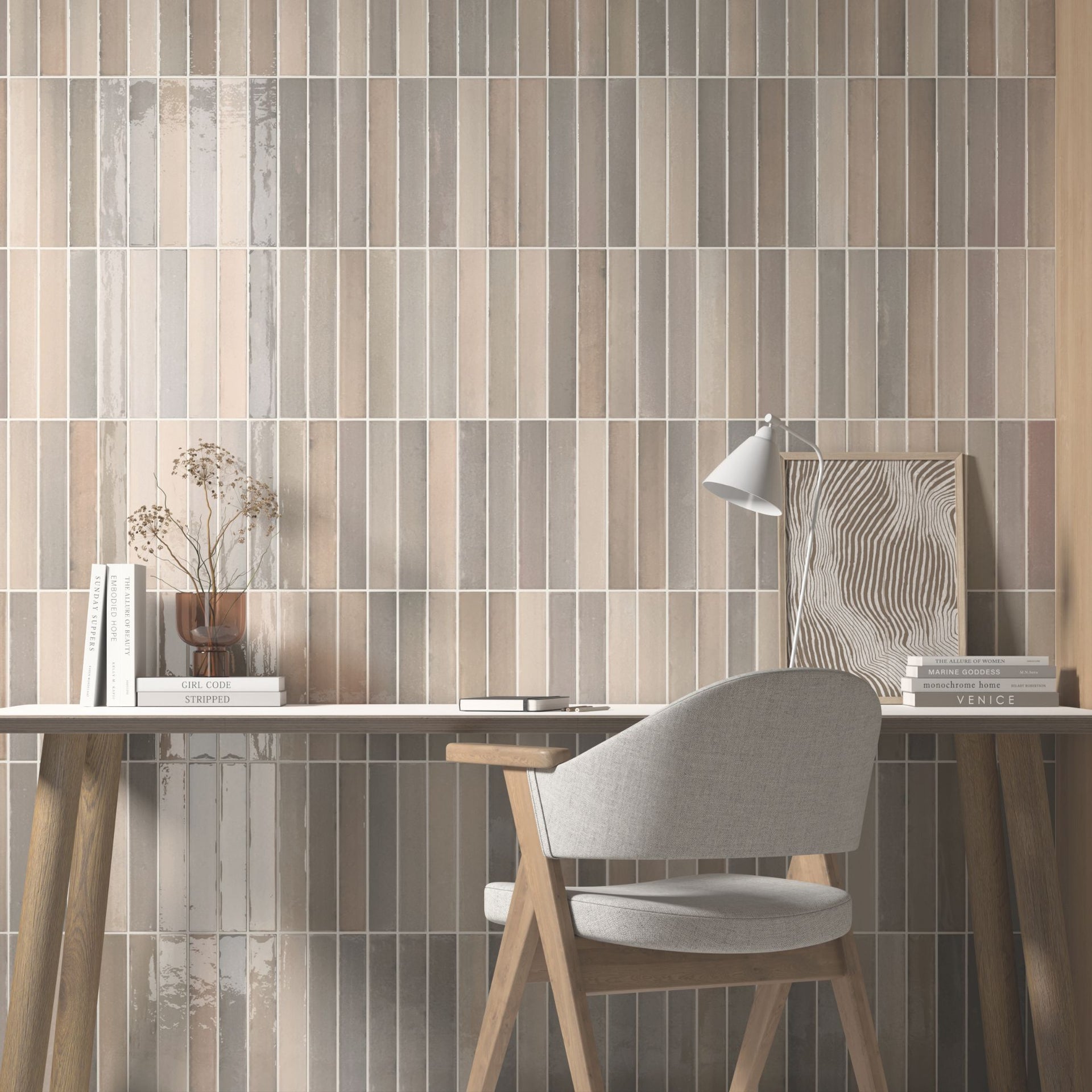 Home office with a wooden and white desk and chair against a Tortosa stone grey tile with varied brown hues on wall.